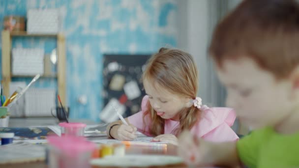 Een klein meisje probeert heel hard te tekenen. Groep kleuterscholen — Stockvideo