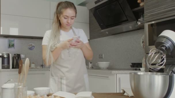 Dona de casa leitura receita no telefone inteligente na cozinha — Vídeo de Stock