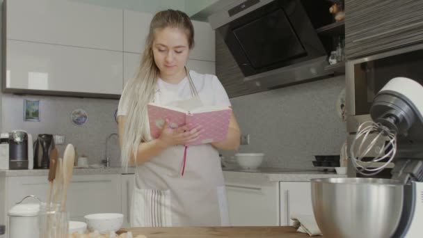 Dona de casa leitura receita no livro de receitas na cozinha — Vídeo de Stock