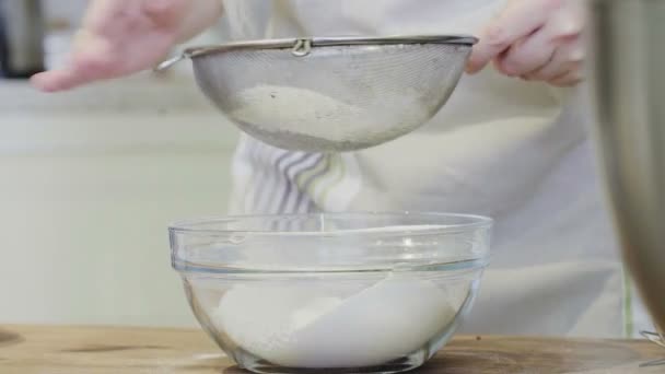 ふるいにかけて小麦粉をふるいます。テーブルの上で小麦粉をふるいにかける女性の手. — ストック動画