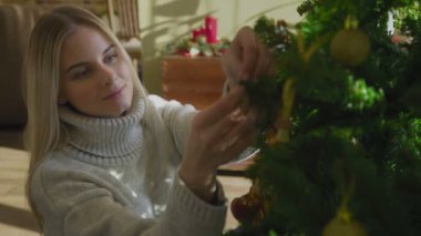 Evdeki Noel ağacını süsleyen sevimli kadının yakın çekimi.