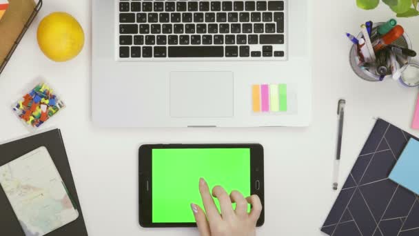 사무실 책상 위의 맨 위 사진 과 녹색 화면 이 있는 화이트 태블릿 컴퓨터와 녹화하고 있는 여성 손. — 비디오