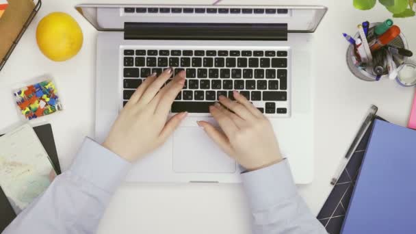 Visão superior das mãos da mulher em camisa azul usando touchpad e digitação no laptop teclado — Vídeo de Stock