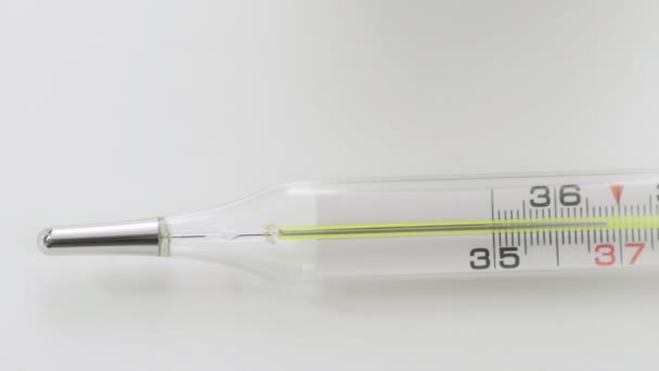 Стеклянный ртутный термометр измеряет температуру на белом фоне Corona. Ковид-19 — стоковое видео