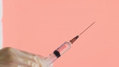 Doktor açık iğne ve pembe arka plan Corona 'ya ilaç serpiyor. Covid 19