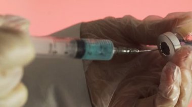 İlacı şırıngadan şırıngaya dolduruyorum. Pembe arka planda mavi bir ilaç Corona. Covid 19