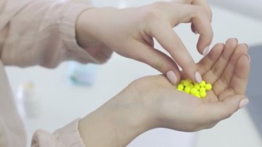Bir sürü küçük ve sarı hap tutan genç bir kadın, Corona 'nın ağzına bir hap alıyor. Covid 19