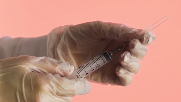 Docteur tenant la seringue et l'aiguille ouverte sur un fond rose Corona. Covid-19 — Video