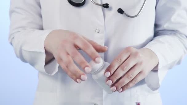 Доктор наливает белые таблетки из бутылки на синий фон Короны. Ковид-19 — стоковое видео