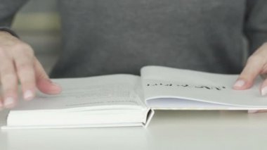 Kadın bir günlük okurken sayfayı çevirir