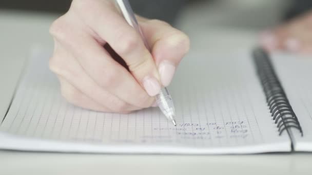 Estudiante escribe con una pluma en un cuaderno — Vídeos de Stock