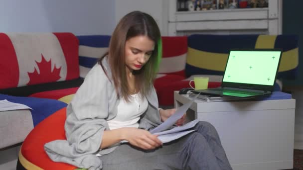 Thuiswerkende vrouw met documenten en een laptop groen scherm — Stockvideo