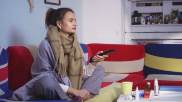 Sjuk ung kvinna tittar på tv och tar ett piller — Stockvideo
