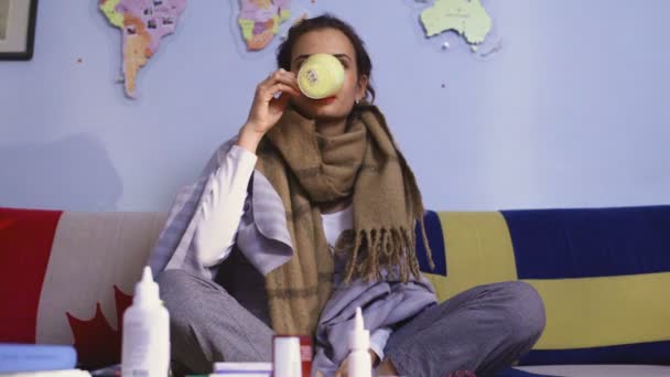 Больная молодая женщина разогревается чаем и пользуется интернетом на смартфоне — стоковое видео