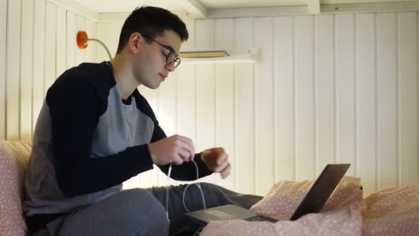 Ung man tittar på video på laptop vid sängen i vandrarhemsrummet — Stockvideo