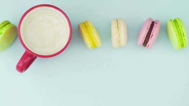 Macaroons ou macaron na superfície azul pastel com café em copo vermelho. — Vídeo de Stock