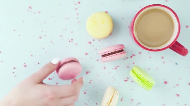 Macarrones o macarones en superficie azul pastel con café en taza roja. — Vídeos de Stock