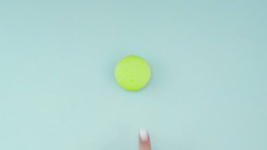 Pastel mavi yüzeyde yeşil mercan ya da badem kurabiyesi. Kapat..