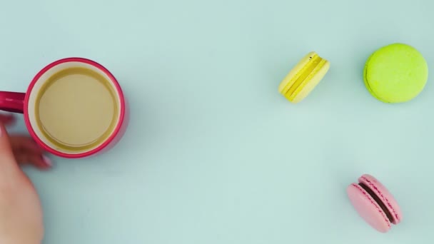 Makronen oder Macaron auf pastellblauer Oberfläche mit Kaffee in roter Tasse. — Stockvideo