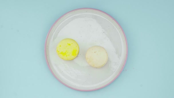 Macarrones de color dulce o macaron en plato blanco sobre superficie azul pastel . — Vídeo de stock