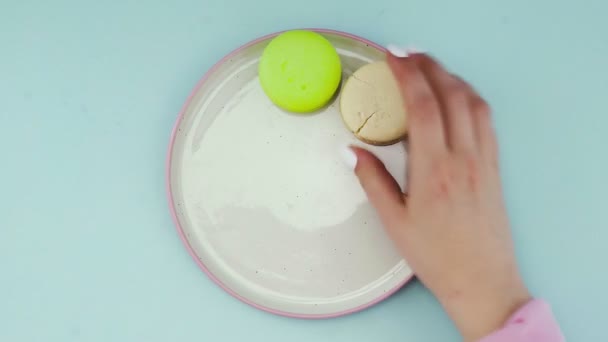 Sladké barvy makróny nebo makaron v bílém talíři na pastelově modrém povrchu. — Stock video