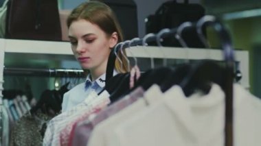 Kadın bluzları askılarda gezer ve bir tanesini denemeye karar verir.