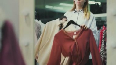 Çekici bayan müşteri soyunma odasında bluz seçiyor.