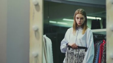 Çekici bayan müşteri soyunma odasında etek seçiyor.