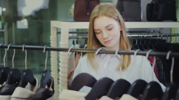 Jovem bela mulher escolher vestido na loja de roupas — Vídeo de Stock