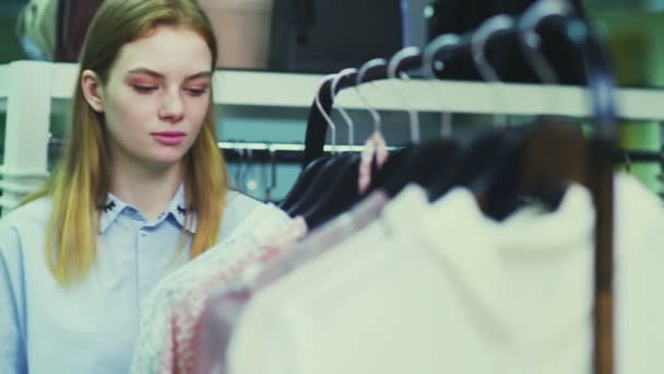 Hermosa mujer comprando ropa en perchas en boutique — Vídeos de Stock