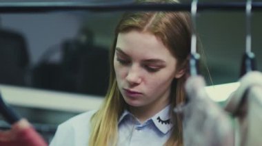 Genç bir kadın şık bir butikte kıyafet seçer, bir kız askılarla ağırlıklı kazakları inceler.
