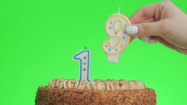 On dokuz numaralı doğum günü mumunu lezzetli bir pastaya koyuyorum, yeşil ekran 19.