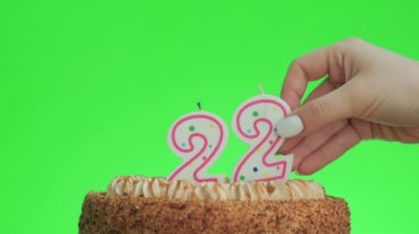 22 numaralı doğum günü mumunu lezzetli bir pastaya koyuyorum, yeşil ekran 22.