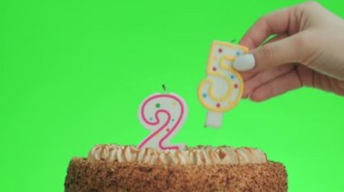 Lezzetli bir pastaya 25 numara bir doğum günü mumu koyuyorum, yeşil ekran 25