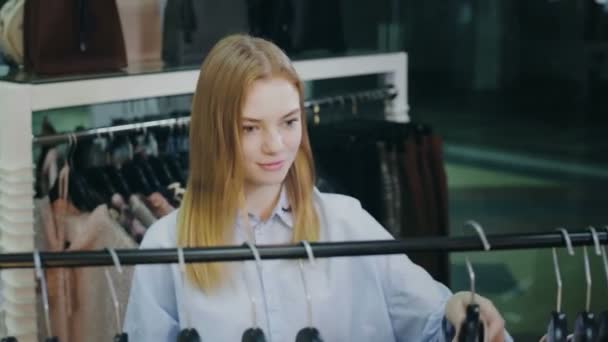 Красивая девушка делает покупки в магазине одежды — стоковое видео