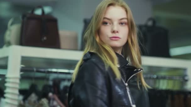 Молода красива дівчина намагається на шкіряній куртці в магазині . — стокове відео