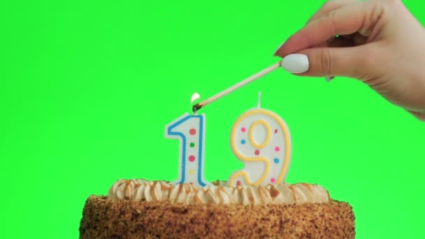 Φωτισμός ενός αριθμού δεκαεννέα κερί γενεθλίων σε ένα νόστιμο κέικ, πράσινη οθόνη 19 — Αρχείο Βίντεο
