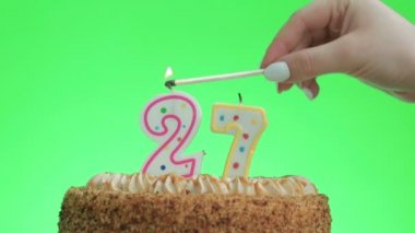 Lezzetli bir pastada 27 numaralı doğum günü mumunu yakıyorum, yeşil ekran 27.