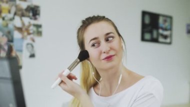 Güzel yüzlü kadın makyaj yapıyor ve müzik dinliyor.