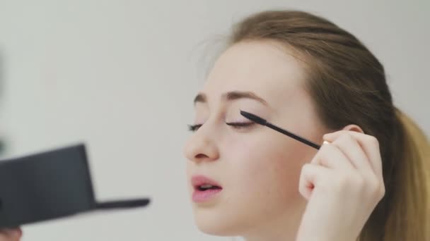 Mujer haciendo maquillaje de ojos por rímel negro, mirando al espejo — Vídeos de Stock