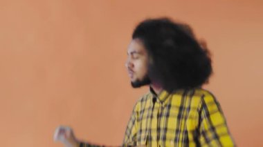 Portakal rengi arka planda dans eden gülümseyen genç Afrikalı adam. Duyguların kavramı