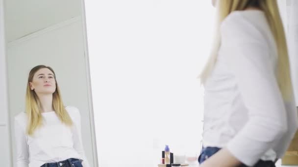 Mooie vrouw die in de spiegel kijkt en haar spiegelbeeld bekijkt.. — Stockvideo