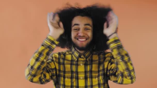 Endişeli Afro-Amerikalı Adam gülüyor, ellerini yüzüne koyuyor ve turuncu arka planda başarıyı kutluyor.. — Stok video