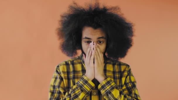 Triste hombre afro-americano sintiéndose molesto en el fondo naranja mirando cámara. Concepto de emociones — Vídeo de stock