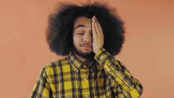 Teleurgesteld afro-Amerikaanse man doet facepalm gebaar tegen Oranje achtergrond. Concept van emoties — Stockvideo