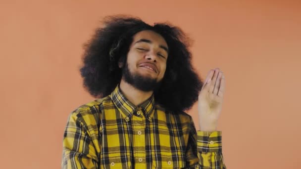 Mladý afroameričan ukazuje na oranžovém pozadí mlčení nebo bla bla gesto. Pojetí emocí