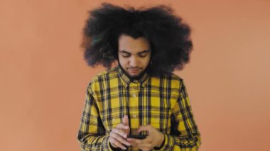 Hüsrana uğramış genç Afro-Amerikan bir adam elinde kırık bir cep telefonuyla turuncu arka planda. Duyguların kavramı