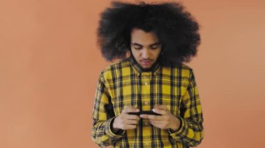 Turuncu arka planda akıllı telefondan Afro-Amerikalı Adam Oyun oynuyor. Duyguların kavramı