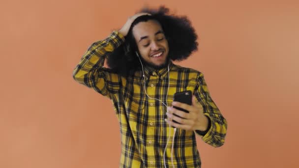 Jonge Afro-Amerikaanse man die belt met een telefoon op Orange achtergrond. Concept van emoties — Stockvideo