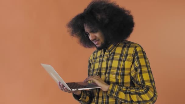 Hombre afroamericano escribiendo en el portátil. No por Shaking Head. Sobre fondo naranja. Concepto de emociones — Vídeos de Stock